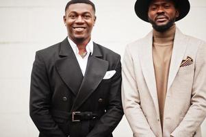 Two fashion black men. Fashionable portrait of african american male models. Wear suit, coat and hat. photo