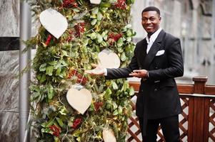 retrato de un joven y apuesto hombre de negocios afroamericano con traje cerca de las decoraciones del árbol de año nuevo. foto