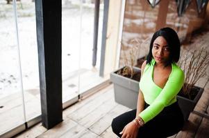 Fashionable african american woman in a light green top and black pants pose. photo