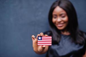 Proud to be liberian. African woman hold small Liberia flag in hands. photo