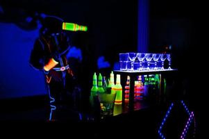 Professional barman and led light show. Silhouette of modern bartender shaking drink at night cocktail bar. photo