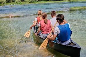 Group adventurous explorer friends are canoeing in a wild river photo