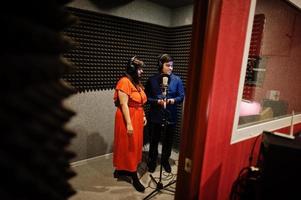 Young asian duet singers with microphone recording song in record music studio. photo