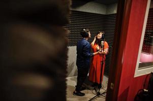 Young asian duet singers with microphone recording song in record music studio. photo