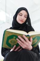 young muslim woman reading Quran at home photo