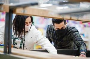 Asian couple wear in protective face mask shopping together in supermarket during pandemic. photo