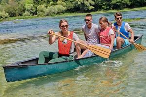 Group adventurous explorer friends are canoeing in a wild river photo