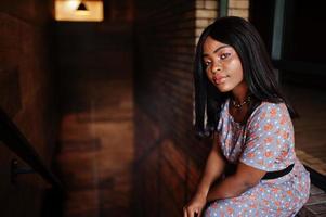 Fashion portrait of african american woman in long dress and eyeglasses indoor. photo