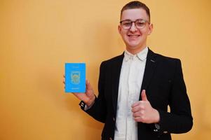 Young handsome man holding Tuvalu passport id over yellow background, happy and show thumb up.  Travel to Oceania country concept. photo