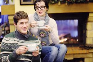 Young romantic couple sitting and relaxing in front of fireplace at home photo