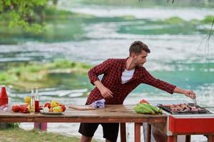 hombre poniendo especias en carne cruda para barbacoa foto