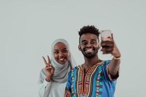A young African couple taking a selfie on their smartphone, my shoes in traditional Sudan clothes. Selective focus. photo