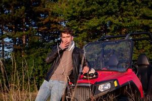 young man taking a break from driving a off road buggy car photo