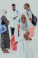 African female student with group of friends in background wearing traditional Islamic hijab clothes. Selectve focus photo