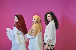 Young muslim women posing on pink background photo