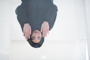 young arabian muslim woman praying on the glass floor at home photo