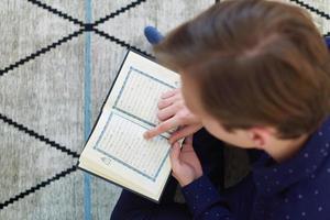 Young muslim man reading Quran during Ramadan photo