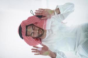 young arabian muslim man praying on the glass floor at home photo