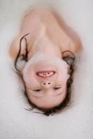 little girl in bath playing with soap foam photo