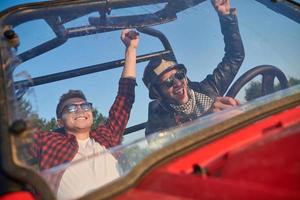 two young happy excited men enjoying beautiful sunny day while driving a off road buggy car photo