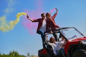 gente emocionada divirtiéndose disfrutando de un hermoso día soleado sosteniendo antorchas coloridas mientras conduce un coche de buggy fuera de la carretera foto