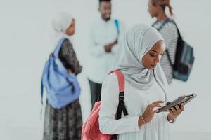 estudiante africana con un grupo de amigos en el fondo usando ropa tradicional islámica de hiyab. enfoque selectivo foto