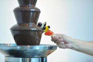 liquid chocolate fountain and fresh fruits on stick photo