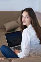 relaxed young woman at home working on laptop computer photo