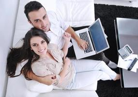 joyful couple relax and work on laptop computer at modern home photo