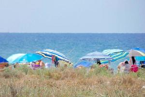 people sunbathing under parasols at the beach photo