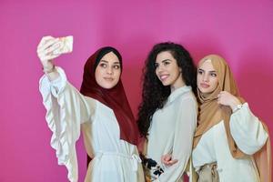 Muslim women taking selfie by mobile phone isolated on pink background photo