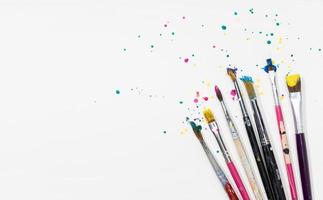 Art Paint brushes with colorful splatter on white canvas paper. Copy space photo