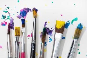 Group of Art Paint brushes and colorful splatter on white canvas paper photo