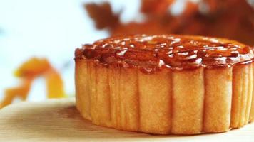Mooncake on wood platter board with autumn leaves background. Traditional Mid-autumn Festival celebration Chinese food.