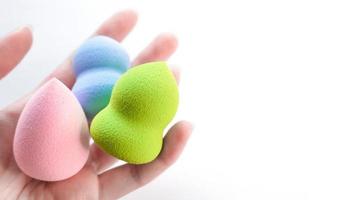 Woman's hand holding a clean makeup sponges on white background. photo