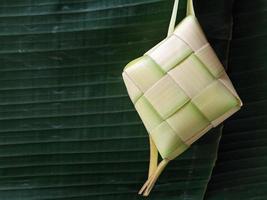 aislado. el ketupat vacío no se ha llenado con arroz. en indonesia, a menudo aparece antes de la celebración de eid al-fitr después del ramadán. concepto de diseño, fondo verde oscuro. foto