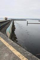 A couple walking on a break water on a cloudy day. photo