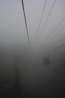 A gondola going up a mountain through thick fog. photo