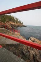 A rocky coastline as seen through a red metal fence. photo