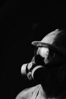 minero de retrato de perfil en casco, respirador y gafas, mirando a la luz. trabajador sucio en camisa.