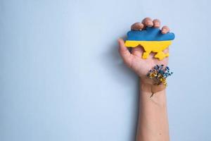 concepto de patriotismo ucraniano. flores azules y amarillas y un mapa de ucrania en la mano de una mujer y en un fondo azul foto