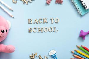 Notebook, note, pens, paper clip, on pastel blue background. Office desk with Back to school text. Flat lay photo