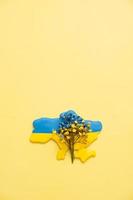 Map of Ukraine with blue and yellow flower on yellow background. Ukrainian symbolic concept photo