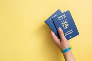 Passports of a citizen of Ukraine in a female hand on a yellow background, close-up. Inscription in Ukrainian Ukraine Passport photo
