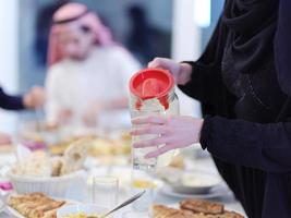 familia musulmana cenando iftar bebiendo agua para romper la fiesta foto