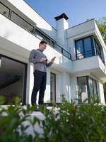 man using mobile phone in front of his luxury home villa photo
