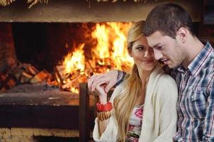 Young romantic couple sitting and relaxing in front of fireplace at home photo