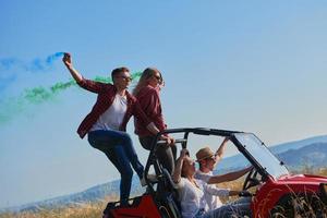 gente emocionada divirtiéndose disfrutando de un hermoso día soleado sosteniendo antorchas coloridas mientras conduce un coche de buggy fuera de la carretera foto