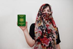 una joven musulmana árabe vestida con hiyab tiene pasaporte de turkmenistán con fondo de pared blanca, retrato de estudio. foto