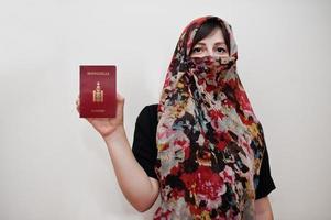 una joven musulmana árabe vestida con hiyab tiene pasaporte de mongolia con fondo de pared blanca, retrato de estudio. foto